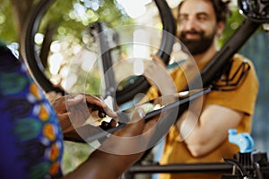 Woman grasping tablet to fix bicycle photo