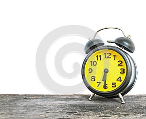 Closeup black and yellow alarm clock for decorate show half past six or 6:30 a.m. on old brown wood desk isolated on white backgro photo