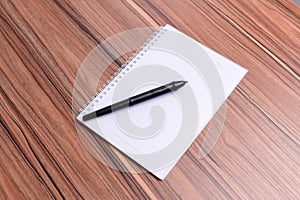 Closeup of the blank copybook with a pen on the table.