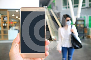 Closeup blank mobile phone screen with blurry woman wearing face mask prevent the flu