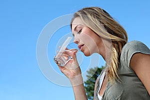 Closeup of blond young woman drinking glass of water