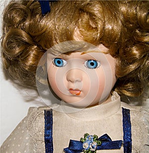 Closeup of a blonde porcelain doll on white background, vintage toys