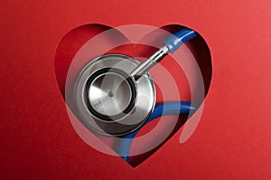 Closeup of blue medical stethoscope and red paper heart shape. Concept of cardiac health