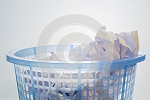 Closeup, Blue mesh waste bin filled of white paper against gradient background