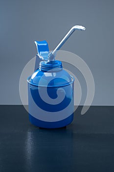 Closeup of blue retro oil gun against dark background