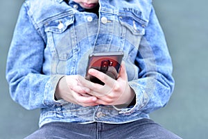 Closeup blurry photo of Teenager holding a black phone in his hand
