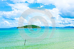 Closeup of boat in sea near island with blue sky and white clou