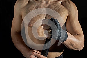 Closeup of a body combat athlete aplying tape on the hands. photo