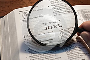 closeup of the book of Joel from Bible or Torah using a magnifying glass to enlarge print.