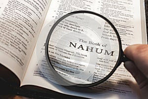 closeup of the book of Nahum from Bible or Torah using a magnifying glass to enlarge print.