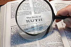 closeup of the book of Ruth from Bible or Torah using a magnifying glass to enlarge print.