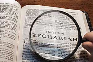 closeup of the book of Zechariah from Bible or Torah using a magnifying glass to enlarge print.