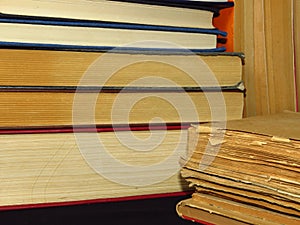 Closeup of books pile. A pile of old books is pictured against dark black background. Old books stacked in a pile.