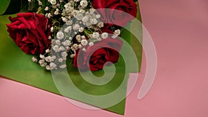Closeup of a bouquet of beautiful red roses on a pink surface