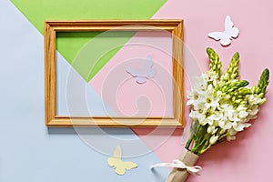 Closeup of the bouquet of white flowers, wooden frame and silhouettes of butterflies on the Pastel colors background