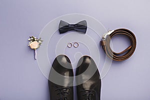 Closeup of bow-tie, belt, shoes, floral corsage, golden rings.