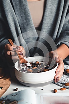 Closeup of bowl with fresh oatmeal and spoon in woman hands, healthy and nutritive breakfast concept.