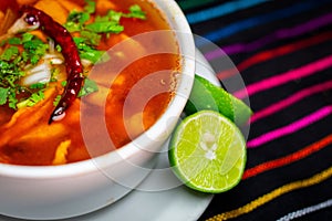 Closeup of a bowl of menudo rojo soup with lime in a Mexican Restaurant