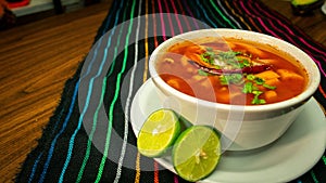 Closeup of a bowl of menudo rojo soup with lime in a Mexican Restaurant