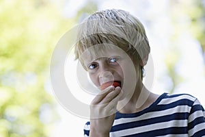 Closeup Of Boy Eating Strawberry Outdoors