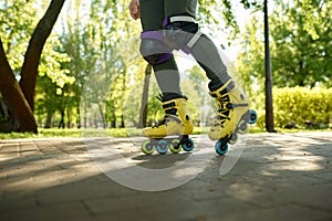 Closeup boy legs wearing roller skates over green nature of urban park