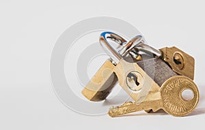 Closeup of a brass key in front of three interlinked padlocks on a white background