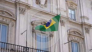 Closeup of Brazilian flag waving at embassy in Rome. Such building hosts consulate of Brazil. Flag of Brazil on flagpole