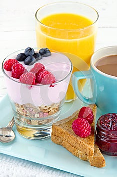 Closeup of breakfast with yoghurt, berries, juice, toast and coffee