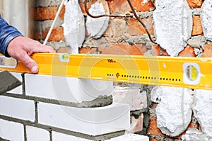 A closeup of a bricklayer worker installing wite blocks and caulking brick masonry joints exterior wall with trowel putty knife ou