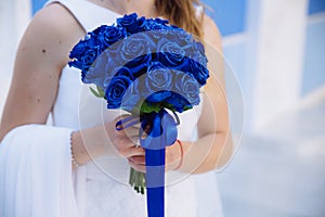 Closeup of bride hands holding beautiful wedding bouquet with blue roses. Concept of floristics