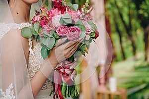 Closeup of bride hands holding beautiful wedding bouquet with white and pink roses. Concept of floristics