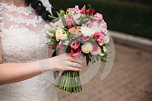 Closeup of bride hands holding beautiful wedding bouquet with white and pink roses. Concept of floristics