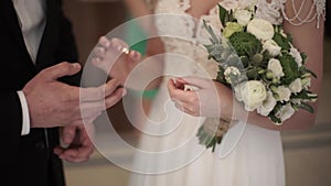 Closeup of a bride putting a gold wedding ring onto the groom`s finger. wedding rings and hands of bride and groom