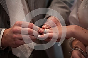 Closeup of bride putting a wedding ring onto the groom& x27;s finger. Couple exchanging wedding rings.