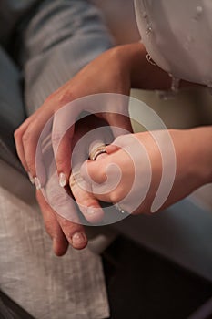 Closeup of bride putting a wedding ring onto the groom& x27;s finger. Couple exchanging wedding rings.