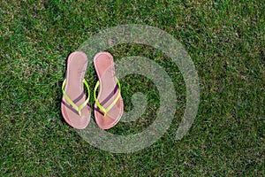 Closeup of bright flip flops and legs on green