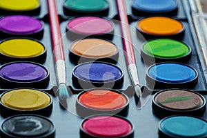 Closeup of bright watercolor paints palette with two brushes