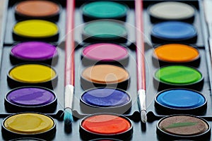 Closeup of bright watercolor paints palette with two brushes