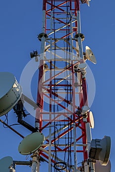 Closeup of a broadcast tower full of devices with a blue sky in the background