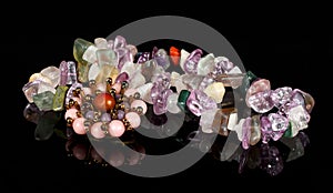 Closeup brooch and beads from crystals of amethyst, fluorite, jasper, carnelian and rose quartz on black acrylic