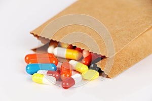 Closeup brown bag with pills falling out, high cost, expensive healthcare