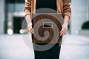 Closeup of a brown dark wooden thick premium photo book in the hands of a girl