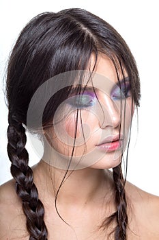 Closeup brunette girl with braids and bright makeup, with bare shoulders, has got closed eyes, over white background