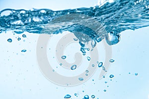 Closeup of bubbles in blue water boiling on white background