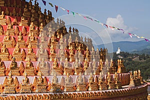 Closeup of Buddha carvings covered in gold at a shrine at Wat Chomkao Manilat, Huay Xai, Laos