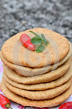 closeup the bunch brown color frayed tortilla with red chilly and green mint in the plastic plate on the soft focus natural brown