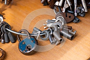 Closeup of a bunch of old vintage keys and a lock attached on a keyring on a wooden table