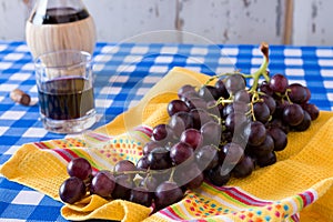 Closeup of a bunch of red grapes and a glass of red wine