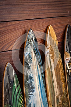 Closeup of a bunch of surfboards leaning against a wooden wall