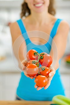 Closeup on bunch of tomato in hand of young woman